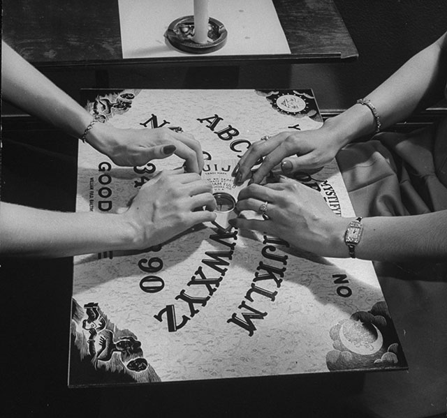 dos personas jugando con una tabla ouija